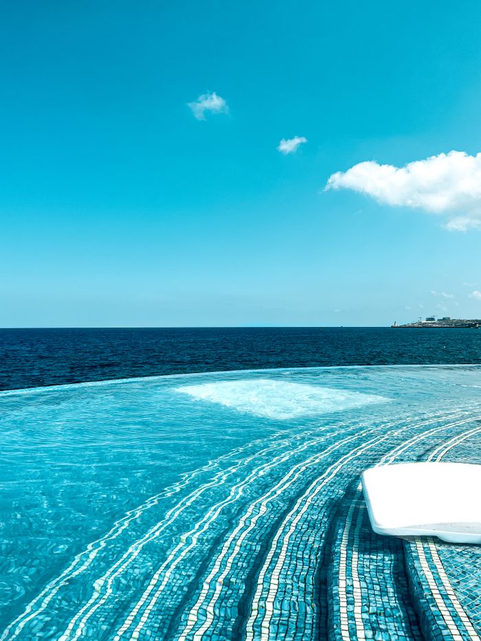 why-choose-us Tranquil infinity pool with stunning ocean view under a clear blue sky, perfect for relaxation.