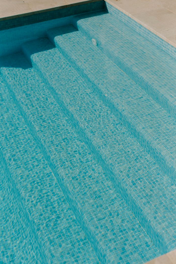 services-02 Turquoise mosaic tiled swimming pool steps under sunlight.