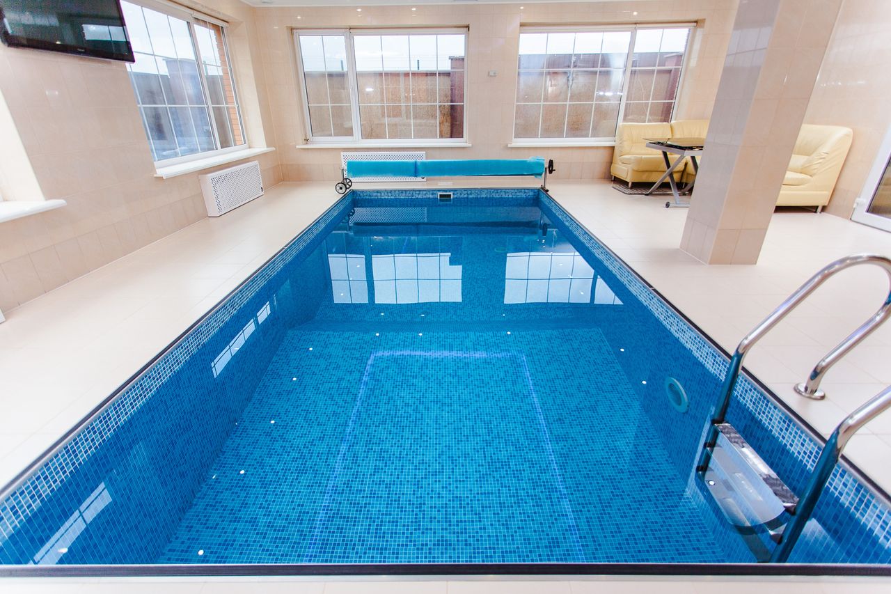 about-01 Bright indoor swimming pool with luxury seating and large windows.