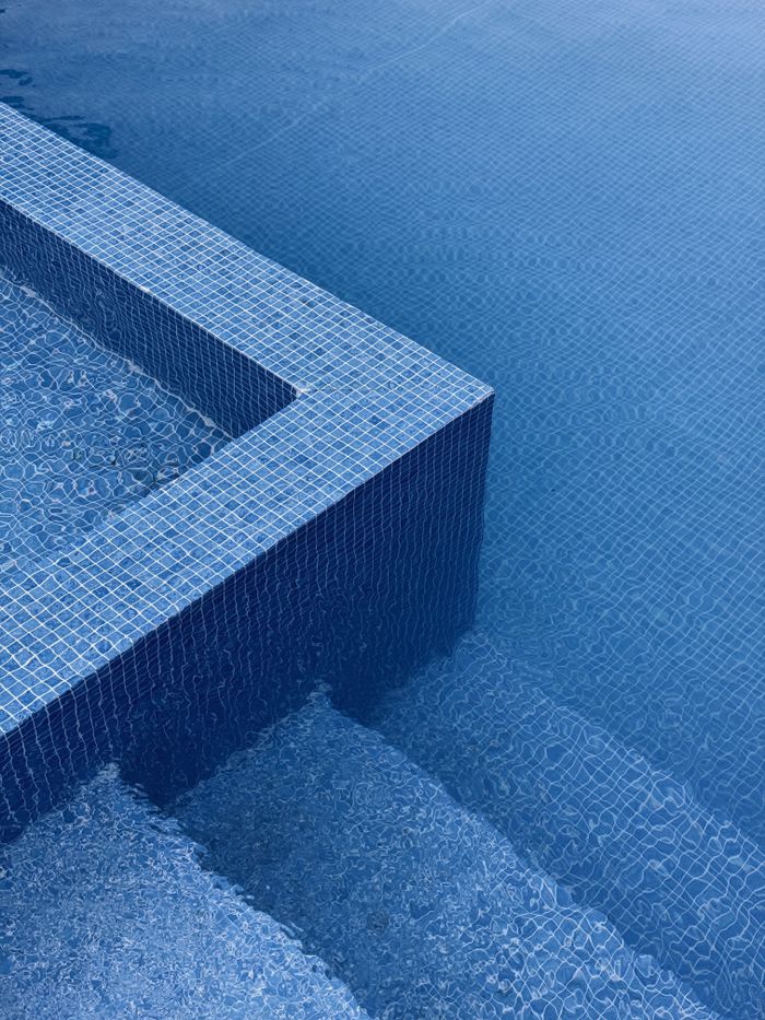 gallery-5 Abstract image of blue tiled pool edges with water ripples, exuding a minimalist and calming vibe.