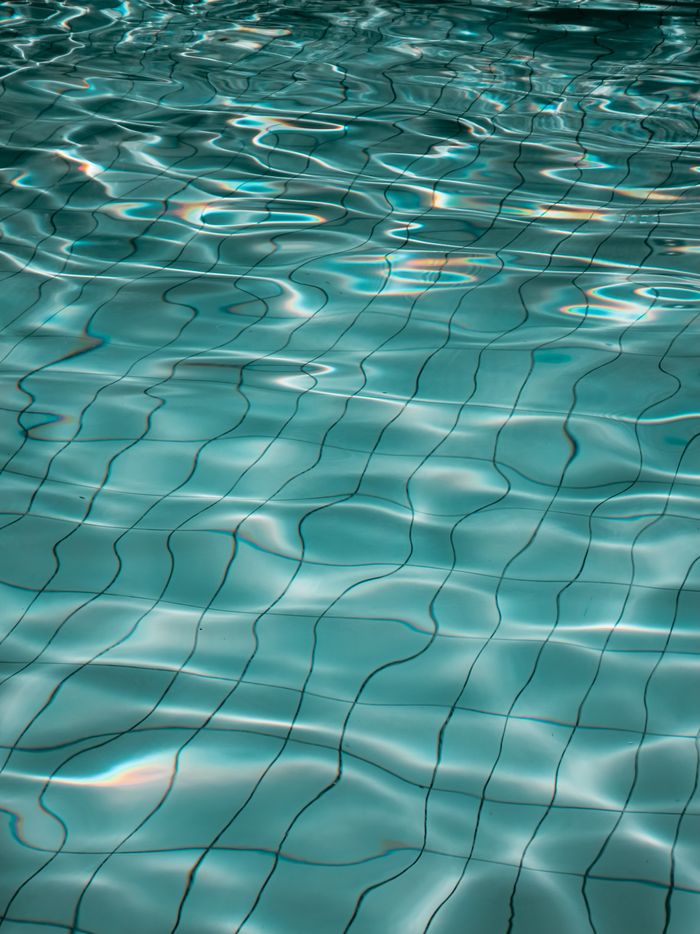 services-03 Serene image of a swimming pool's water surface with gentle ripples and reflections.