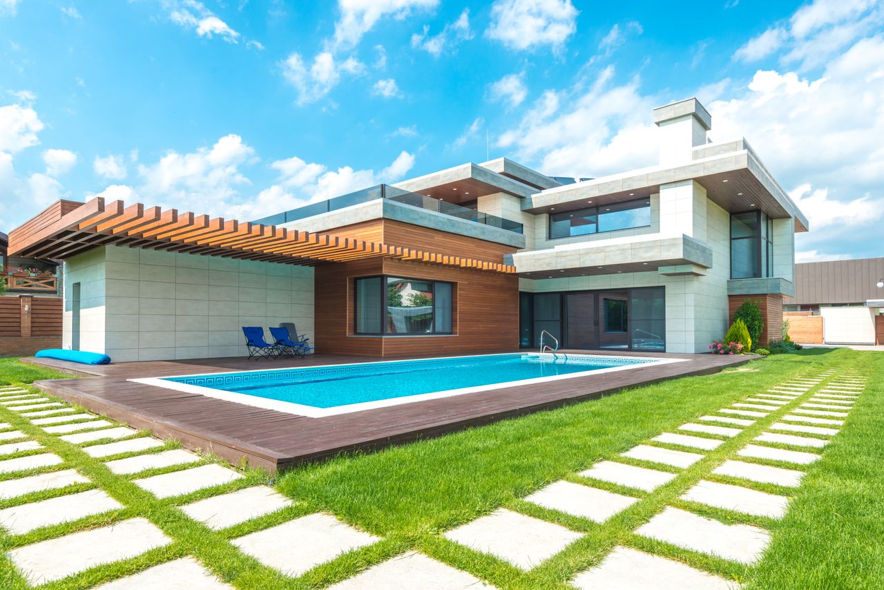 services-img Contemporary house with pool, lush lawn, and clear skies.